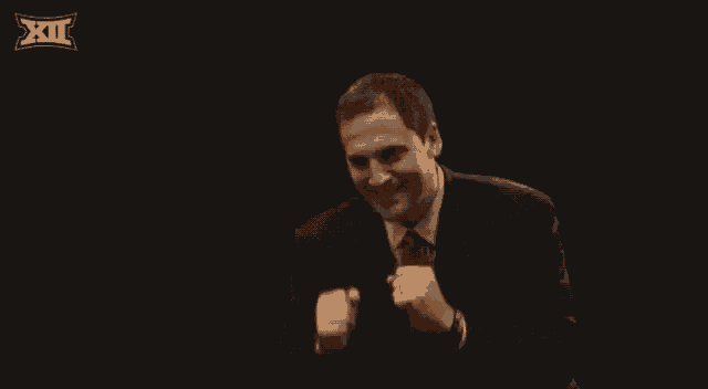a man in a suit and tie is smiling in front of a black background with the xii logo on it