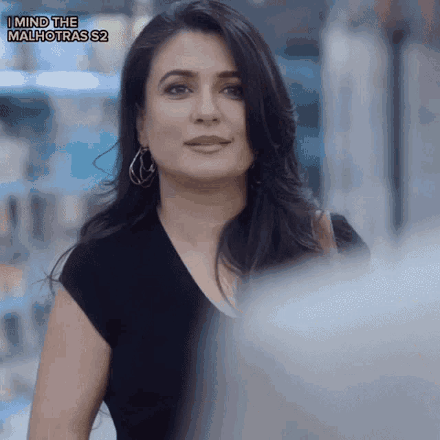 a woman in a black shirt with the words i mind the malhotras s2 on the bottom