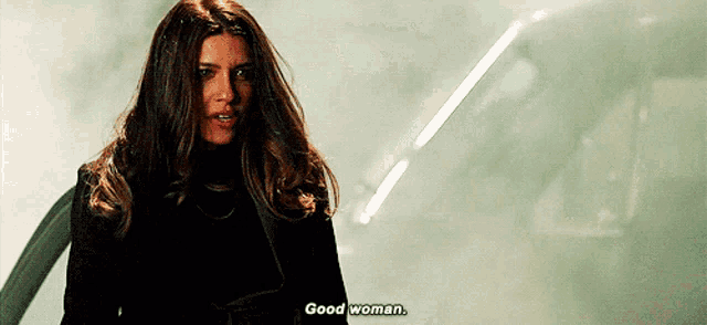 a woman is standing in front of a car and says good woman