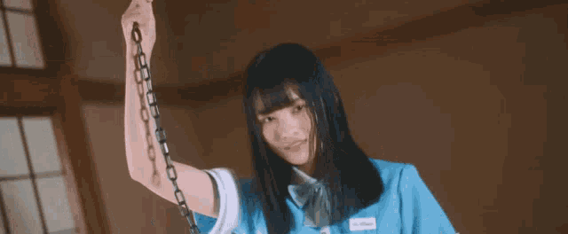 a girl in a blue shirt is holding a chain around her arm .