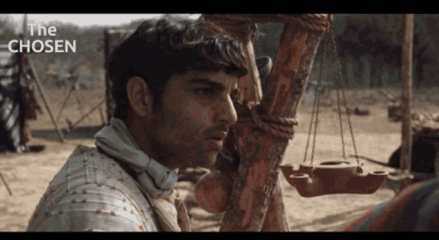 a man in armor is standing next to a wooden post with the words the chosen above him