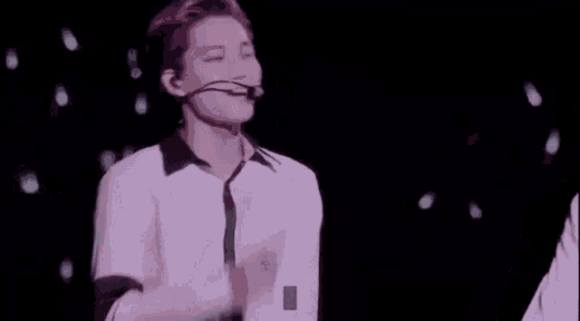 a man in a white shirt and tie is dancing on a stage with a microphone .