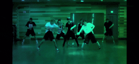 a group of people are dancing in a room with a red door