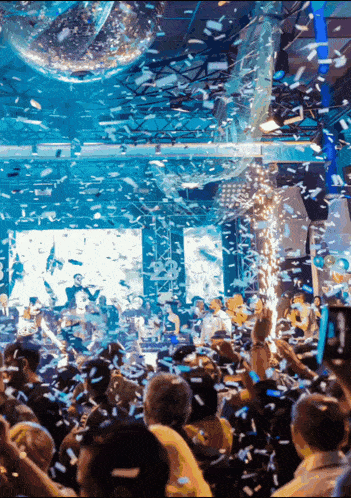 a crowd of people at a party with confetti falling on them