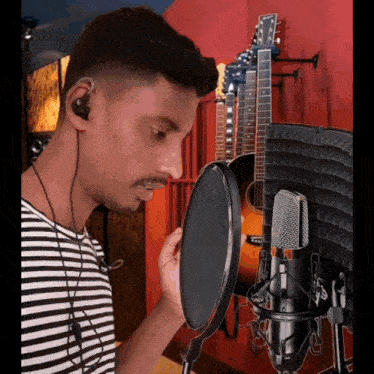 a man is singing into a microphone in front of a guitar