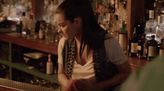 a woman in a white shirt is standing behind a bar counter