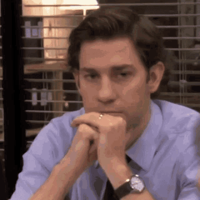 a man is sitting at a table with his hands on his chin .