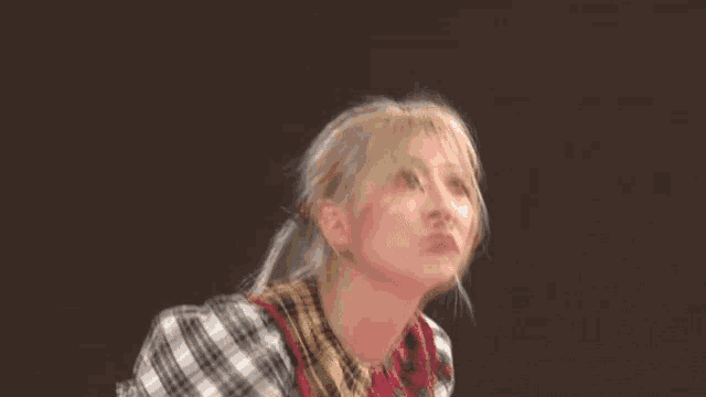 a woman wearing a plaid shirt is making a face