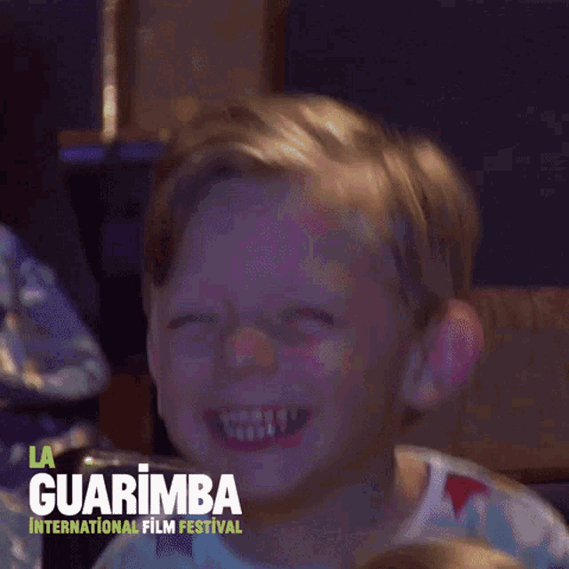 a young boy is smiling in front of a sign that says la guarimba