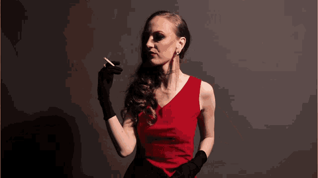 a woman in a red dress is holding a cigarette in her hand
