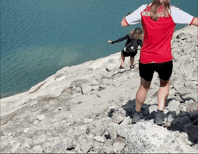 a girl wearing a red shirt that says cool noodle climbs a rocky hill