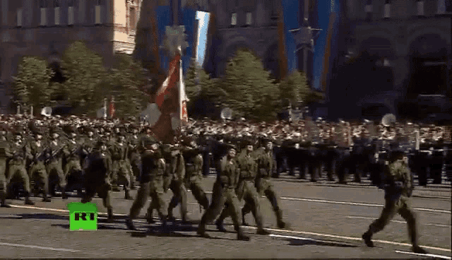 a large group of soldiers marching down a street with a green rt logo in the corner