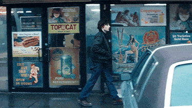 a man walking in front of a store with a sign that says top cat