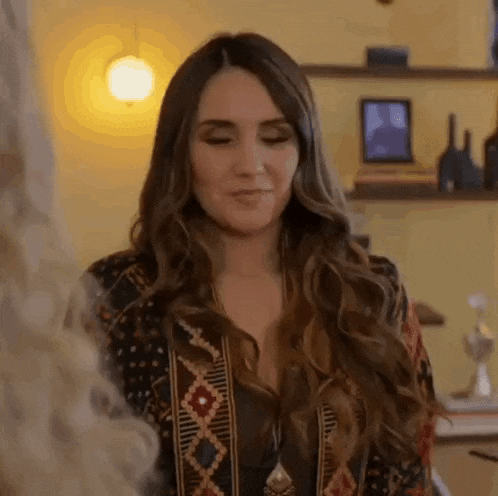 a woman with long hair is standing in a room with her eyes closed and looking down .
