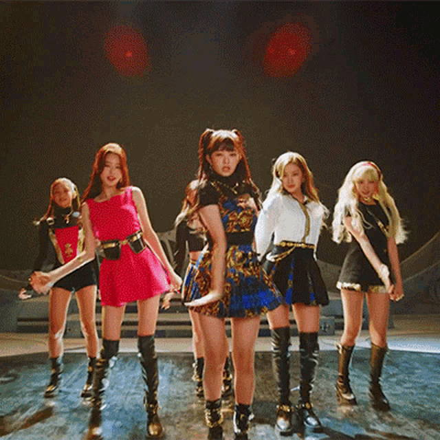 a group of women are standing on a stage holding hands and dancing