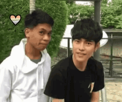 a couple of young men are standing next to each other and looking at the camera .