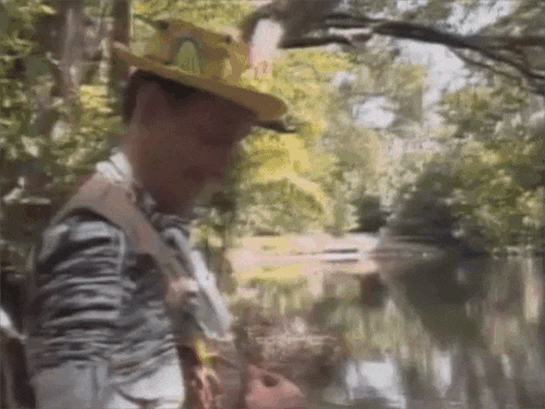 a man wearing a cowboy hat is playing a guitar in a forest .