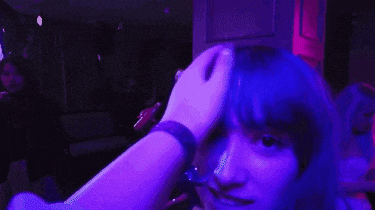 a woman with blue hair is being held by a man in a dark room .