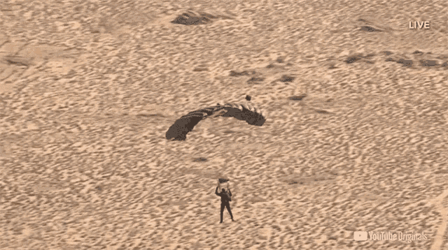 a man is flying through the air with a parachute in the desert and the words live on the bottom