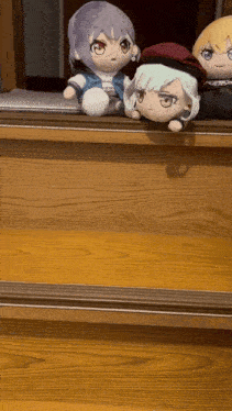 three stuffed animals are sitting on a wooden shelf