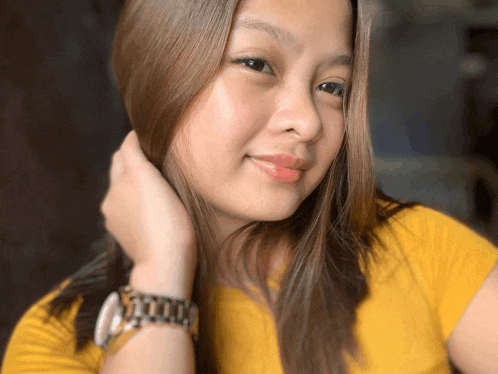 a woman wearing a yellow shirt and a watch