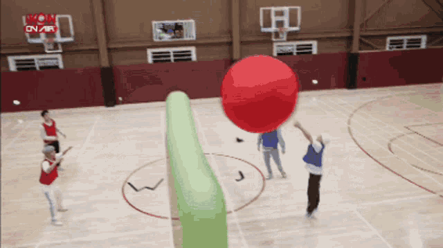 a group of people are playing a game of dodgeball on a basketball court sponsored by mon on air