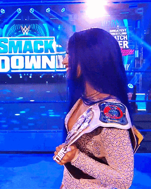 a woman holding a trophy in front of a smack down sign