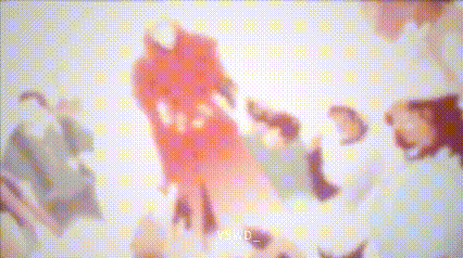 a group of people are standing around each other in a room with a red and white background .