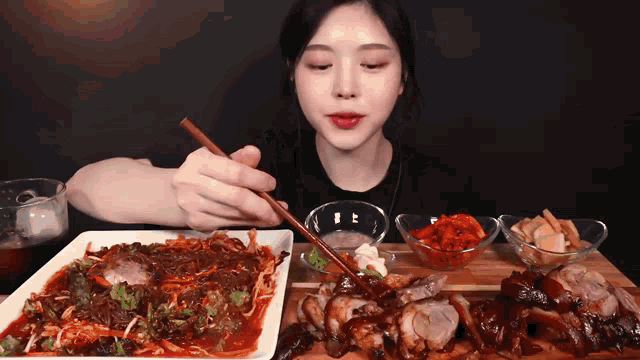 a woman is eating a plate of food with chopsticks and a glass of beer