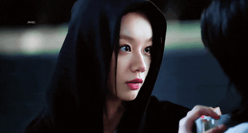 a woman wearing a black hoodie is looking at another person .