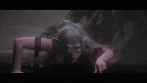 a woman with horns is crawling on the ground in a dark room in a video game .