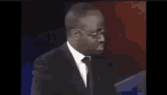 a man in a suit and tie is standing in front of a podium .