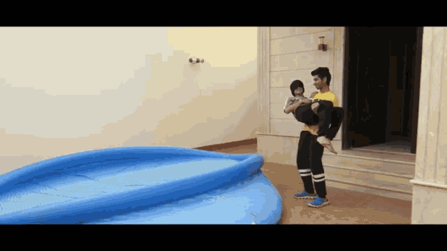 a man is carrying a child in his arms in front of a large inflatable pool