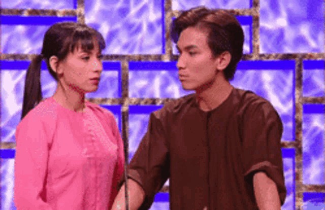 a man and woman are standing next to each other and looking at each other .