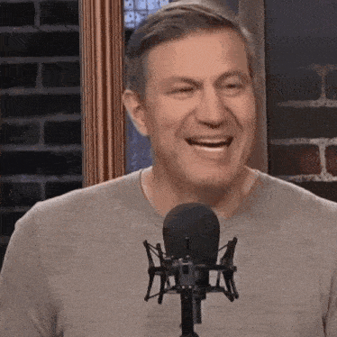 a man is smiling in front of a microphone in a studio .