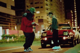 a man in a red jacket is standing next to a red car
