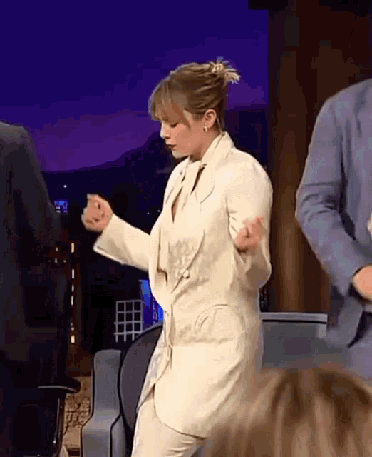 a woman in a suit is dancing on a stage