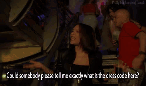 a woman says " could somebody please tell me exactly what is the dress code here " in a dark room