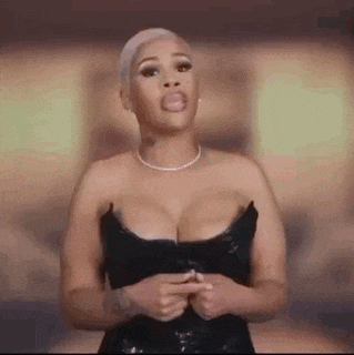 a woman in a black dress is making a funny face while standing in front of a camera .