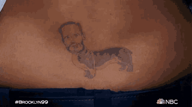 a man has a tattoo of a man 's face and a dog on his back