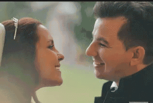 the bride and groom are looking at each other and smiling .