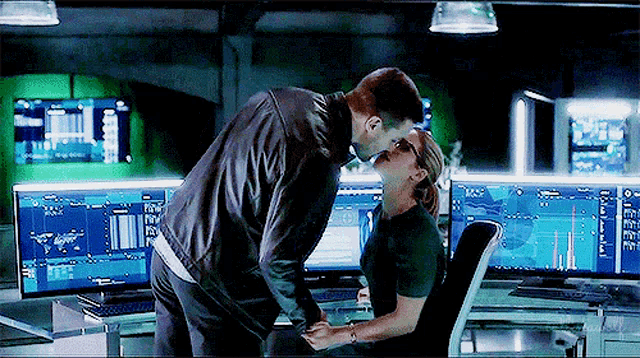 a man and a woman are kissing in front of a computer .