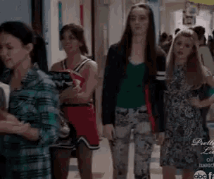 a group of girls are walking down a hallway .