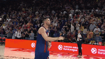 a basketball player stands on the court in front of a turkish airlines banner