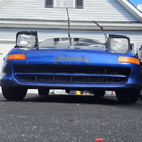a blue car is parked in a driveway in front of a house