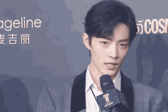 a man in a suit is talking into a microphone with the word cosmo on it