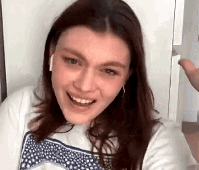 a woman wearing headphones and a white t-shirt is smiling .