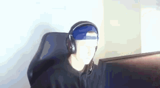 a man wearing headphones and a hat is sitting in front of a computer .