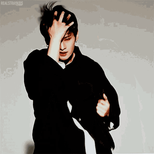 a man in a black shirt holds his hand to his forehead