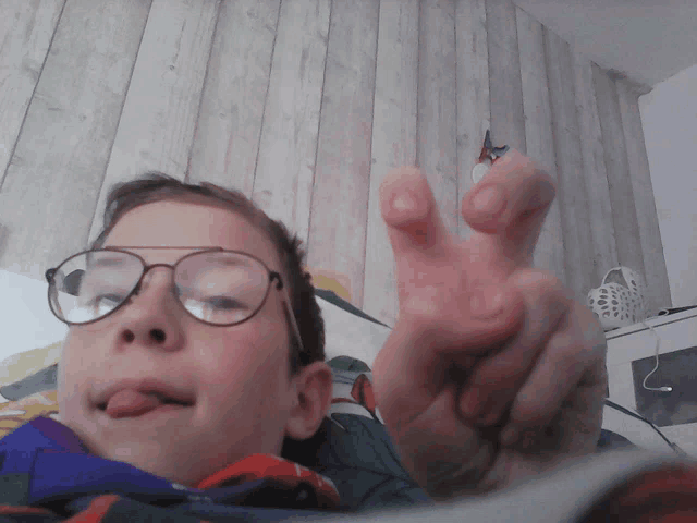 a young boy wearing glasses makes a peace sign